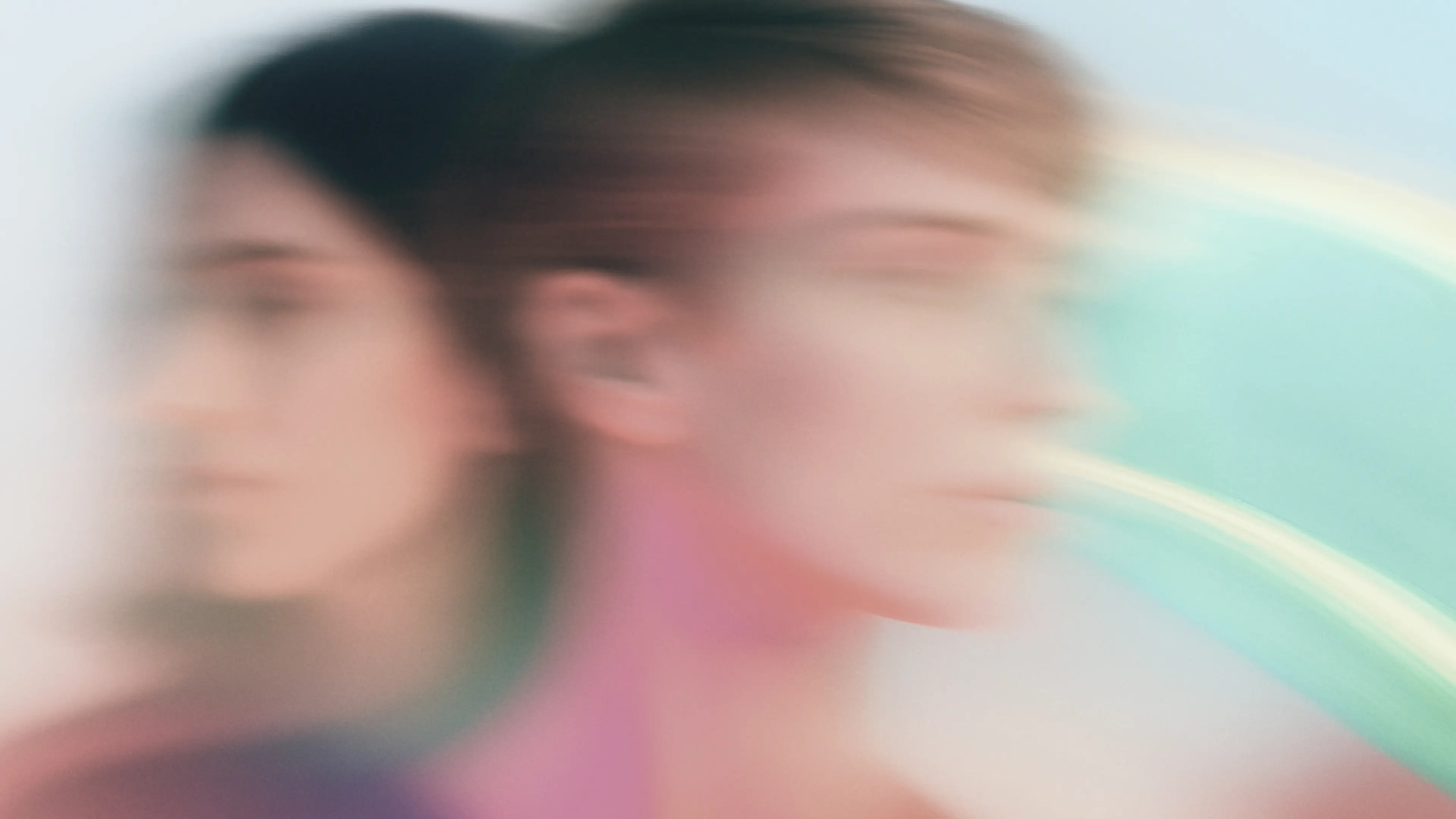 Digital Systems Zwei Frauen, Rücken an Rücken stehend, mit Bewegunsunschärfe vor einem bunten Hintergrund.